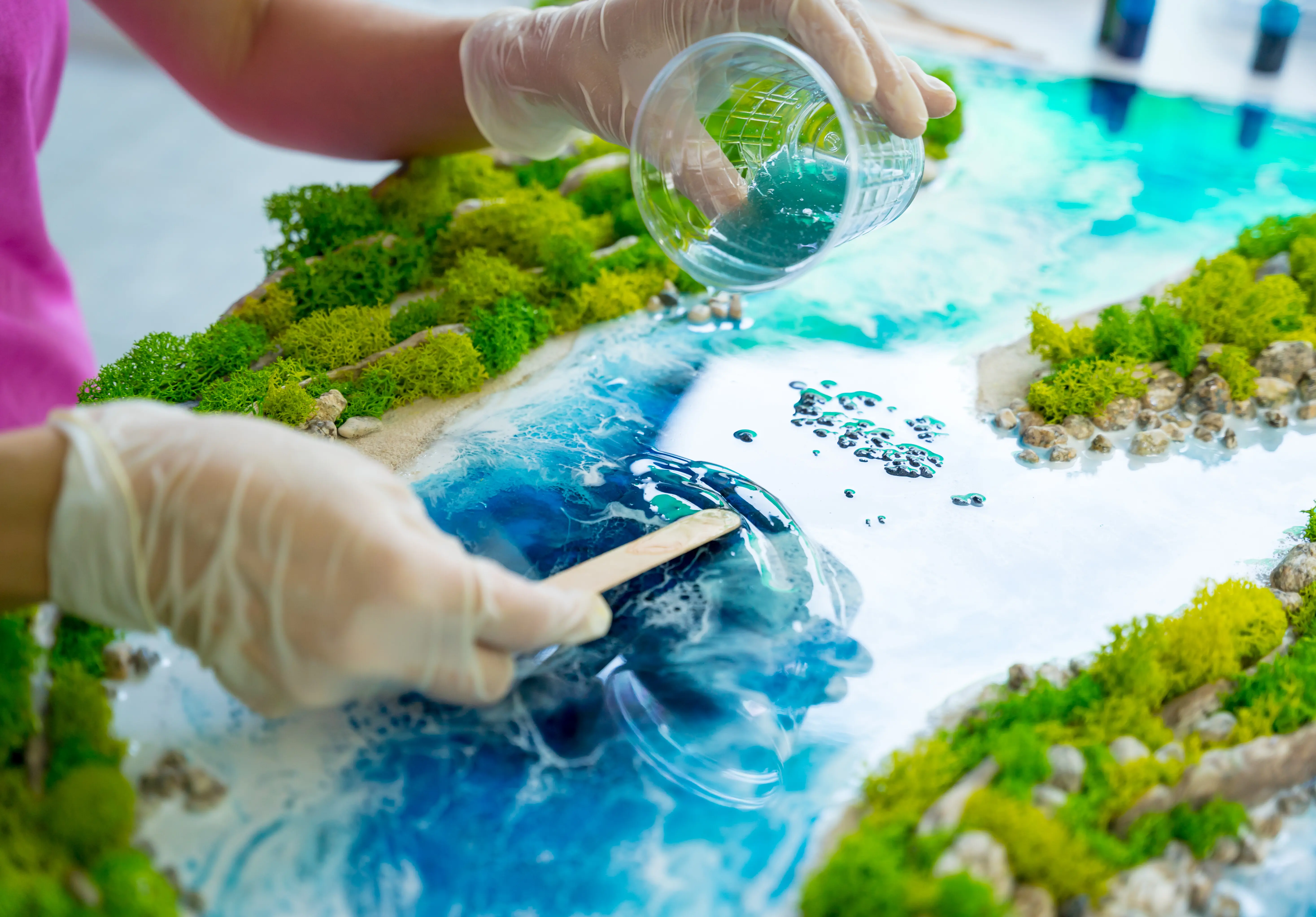 Der Herstellungsprozess eines Kunstdekors aus Epoxidharz, Natursteinen und Moos.